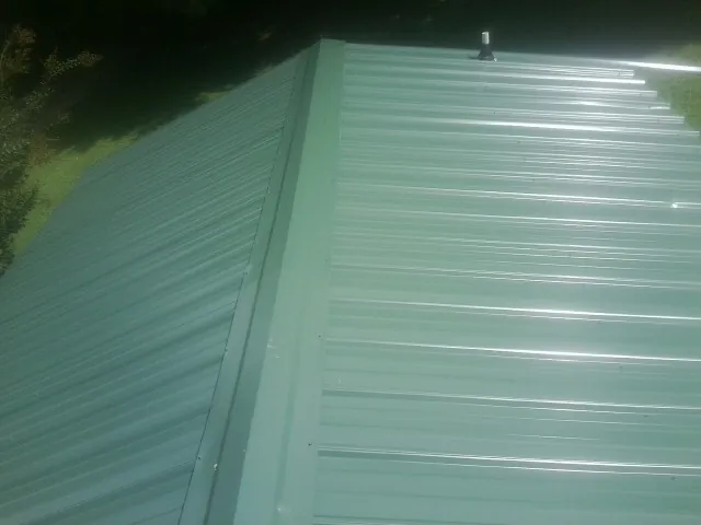 New green metal panels meeting at the ridge of a roof — Flat Roof Repair work by our crew in Rowland Heights