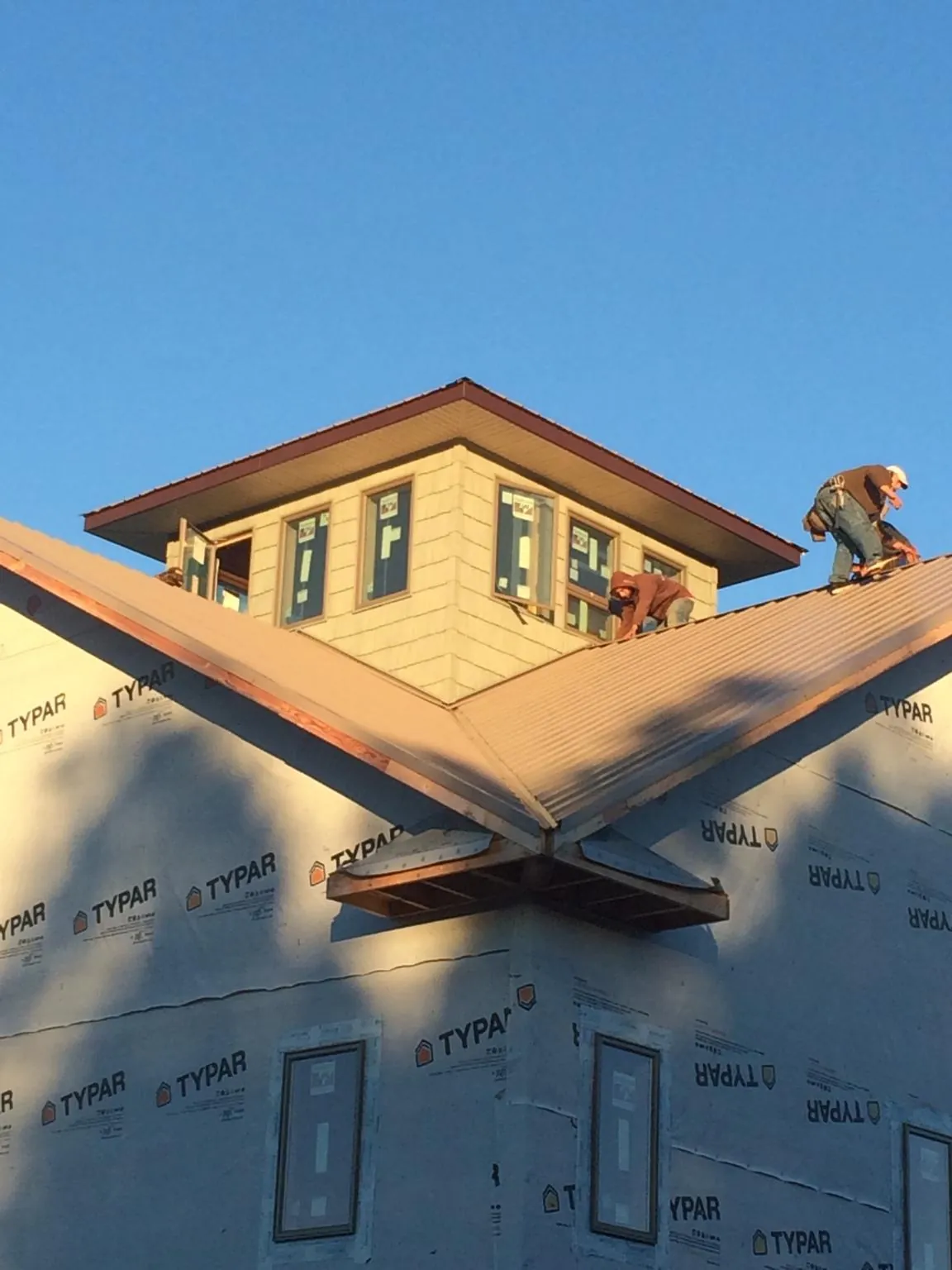 Roofers working around a rooftop cupola on a new metal roof at sunset — Roof Waterproofing in Rowland Heights by Roofing Brothers